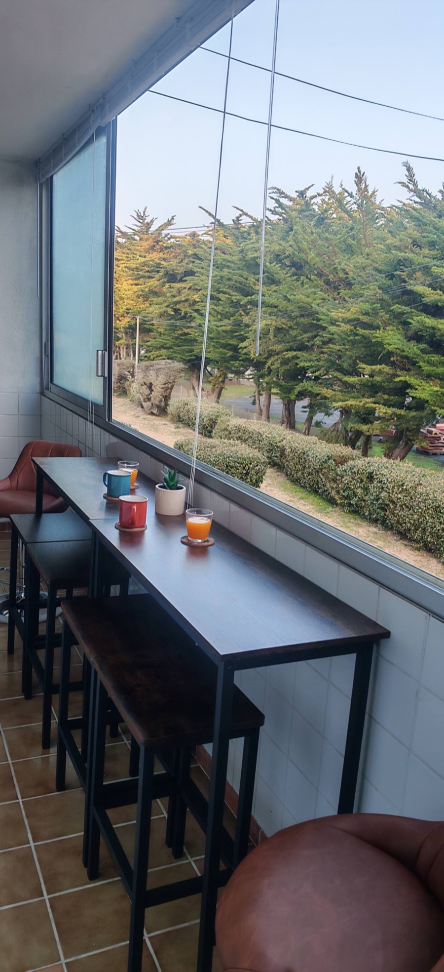 La loggia vitrée et ses tables hautes face aux pins