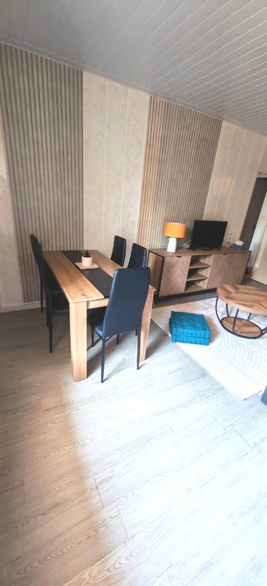 Le coin repas et le salon, murs en tasseaux de bois clair
